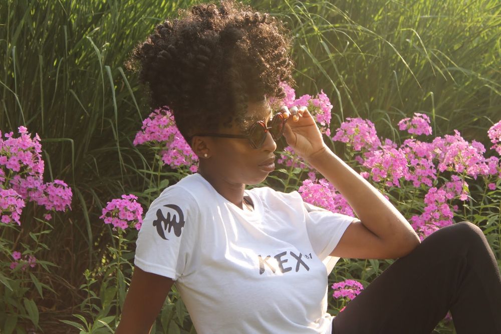 People in white t-shirts posing among pink flowers in a garden setting.