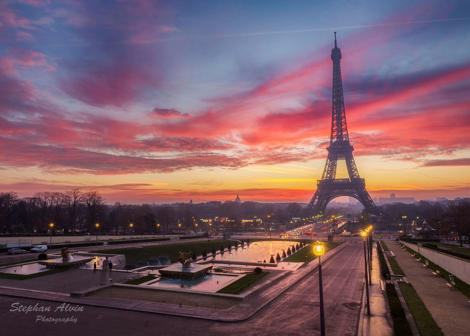 Eiffel Tower silhouetted against a spectacular pink and orange sunrise sky in Paris.