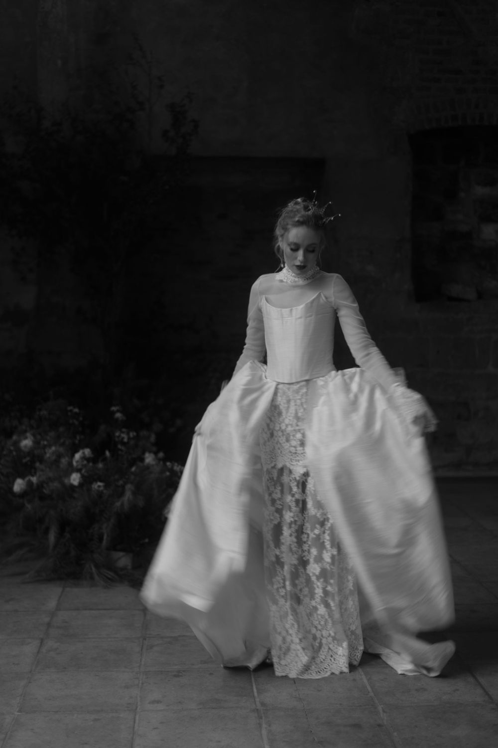 Black and white photograph of period wedding dress with dramatic full skirt and lace details.
