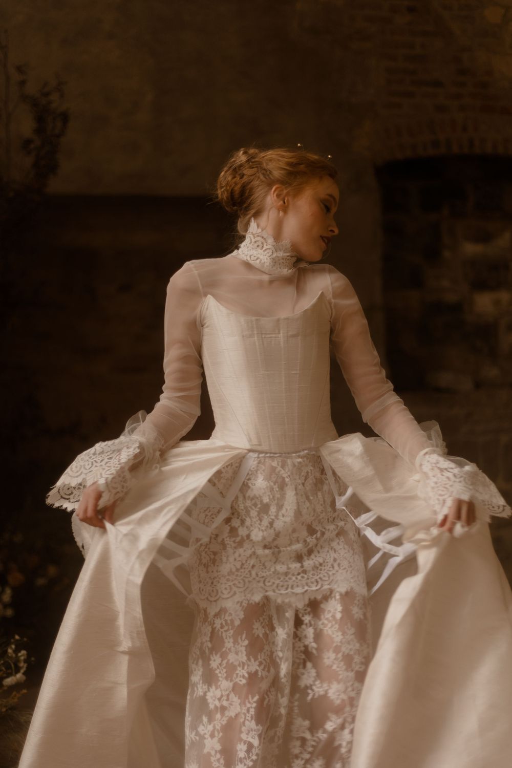 Close-up of Victorian-inspired wedding dress with high neck and lace details in warm tones.