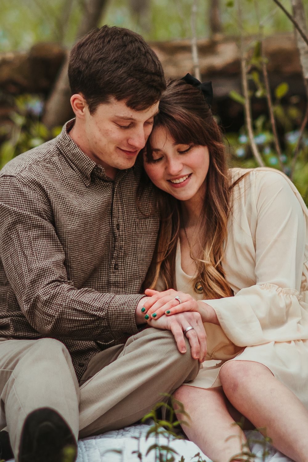A couple shares a tender moment on a wooden bench in a garden setting.