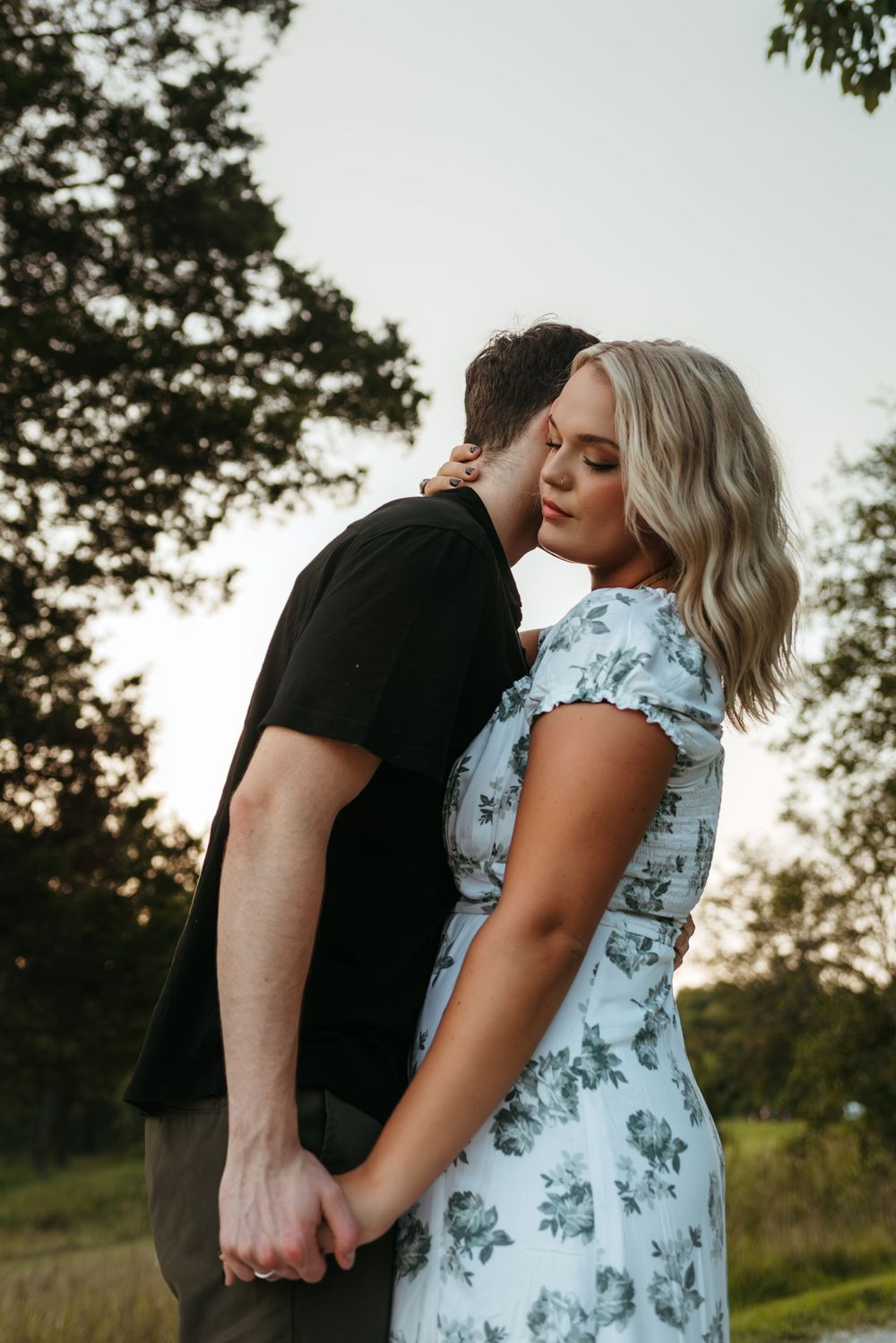 A couple embraces during a sunset photoshoot in a natural outdoor setting.