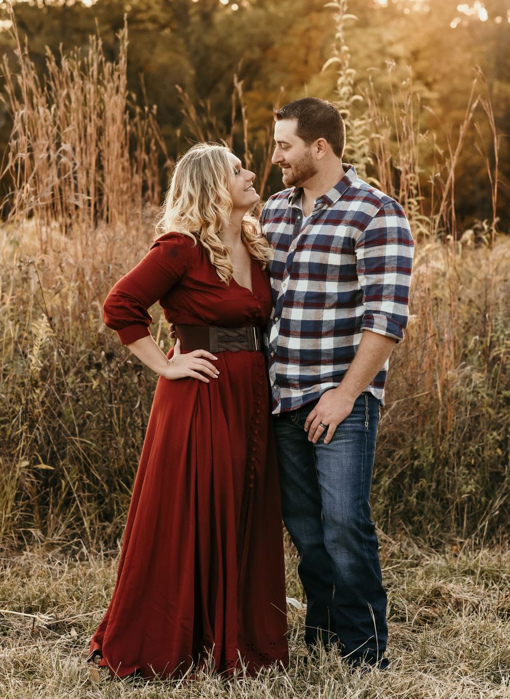 A romantic sunset photoshoot in tall grass featuring a couple in casual fall attire.