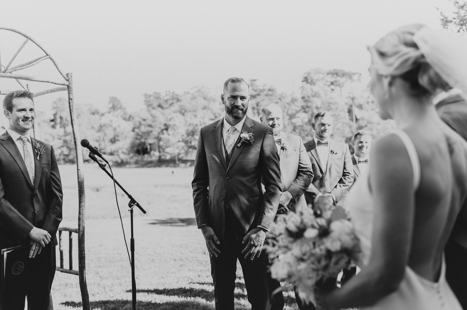 Black and white capture of an intimate outdoor wedding ceremony with rustic decor.