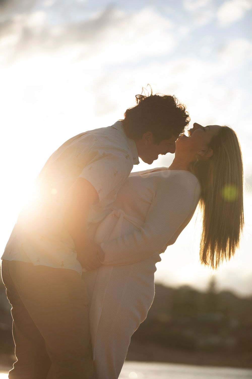 Romantic backlit silhouette of a couple embracing during golden hour.
