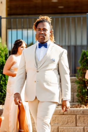 Wedding party member wearing crisp white suit with blue bowtie in outdoor setting. Middle TN wedding photographer
