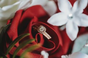 Close-up of diamond engagement ring nestled among red and white flowers. Middle TN wedding photographer