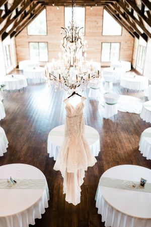 Elegant white wedding dresses displayed on hangers in a rustic barn venue with crystal chandeliers.Middle TN wedding photographer