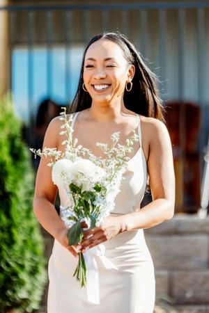 Person in white dress holding delicate white flower bouquet while smiling joyfully. Middle TN wedding photographer