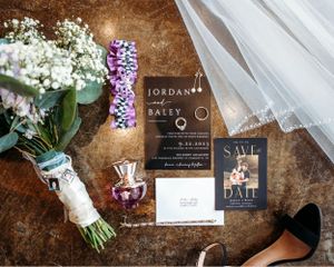 Wedding details including invitations, flowers, and accessories arranged on a brown textured surface. Middle TN wedding photographer