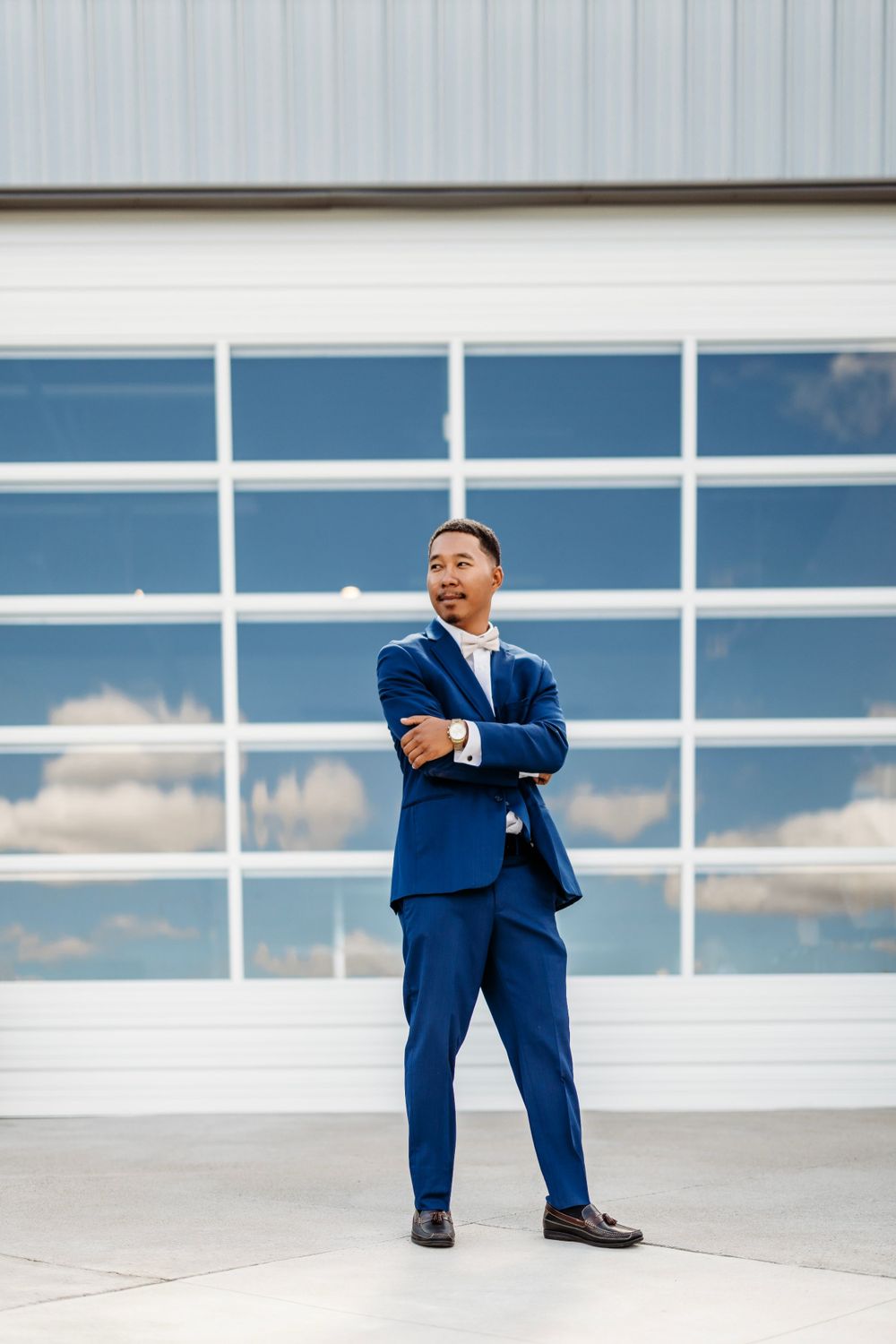 Men in blue suits pose creatively against a modern white building with glass windows.Middle TN wedding photographer