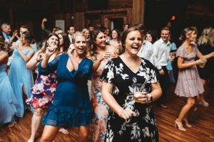 Wedding reception guests dancing and celebrating on a wooden dance floor under indoor lighting. Middle TN wedding photographer