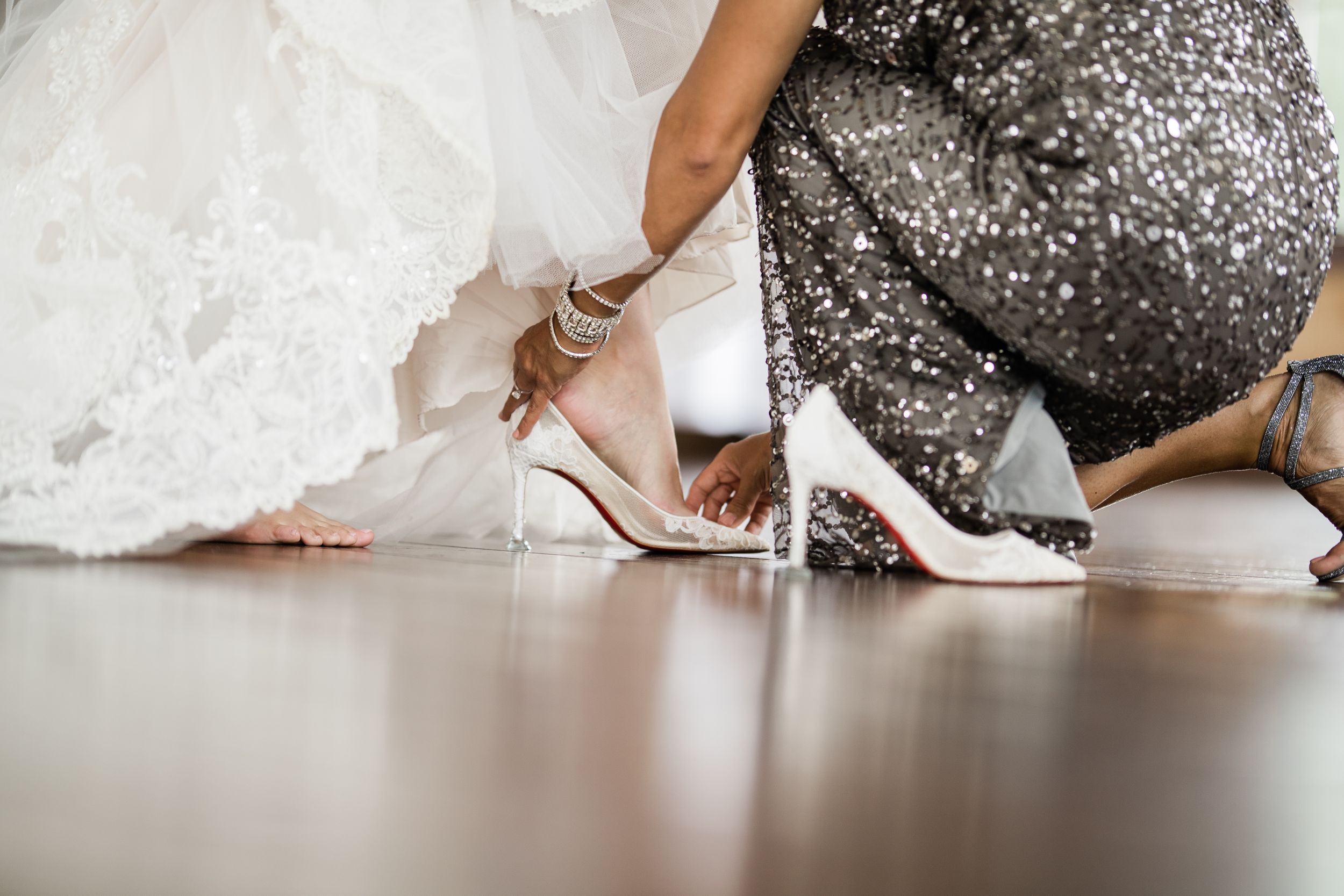 Close-up of wedding dress and sparkly bridesmaid dress details on hardwood floor.Middle TN wedding photographer