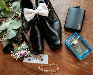 Wedding accessories including bow tie, shoes, and jewelry arranged on wooden surface.Middle TN wedding photographer