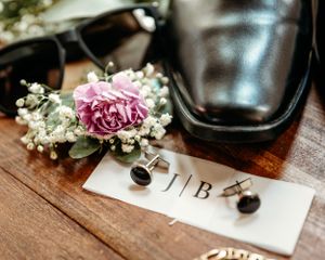 Wedding details featuring black dress shoes and delicate floral elements on wooden background.Middle TN wedding photographer