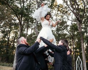 Wedding guests toss bride during an outdoor celebration. Middle TN wedding photographer
