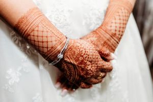 Close-up shots of hands adorned with intricate henna designs against a white dress. Middle TN wedding photographer