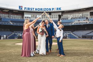 Wedding celebration group photo taken on baseball field with First Horizon Park signage visible. Middle TN wedding photographer