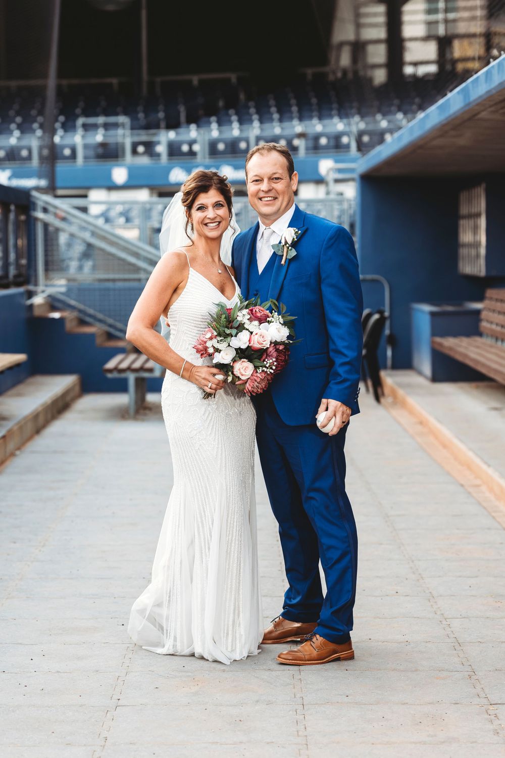 Wedding couple poses for photos on concrete walkway in baseball stadium. Middle TN wedding photographer