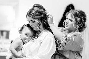Black and white photo of bridal preparation showing tender moment with baby while getting hair styled. Middle TN wedding photographer