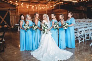Wedding party in light blue bridesmaid dresses and white gown lined up in a rustic barn venue. Middle TN wedding photographer