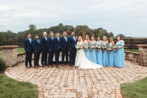 Wedding party posed on brick patio with bridesmaids in blue dresses and groomsmen in navy suits.Middle TN wedding photographer