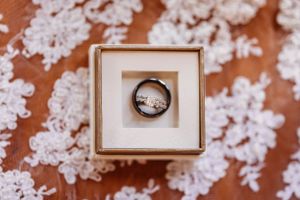 Wedding rings photographed on textured coral surface with delicate white floral details.Middle TN wedding photographer