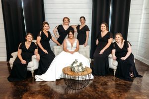 Group photo showing bridesmaids in black dresses with bride in white at an indoor venue. Middle TN wedding photographer