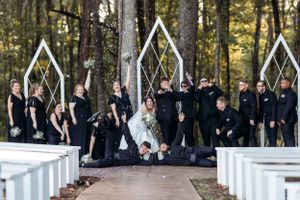 Wedding party stand in rows along white pillars during an outdoor forest ceremony. Middle TN wedding photographer