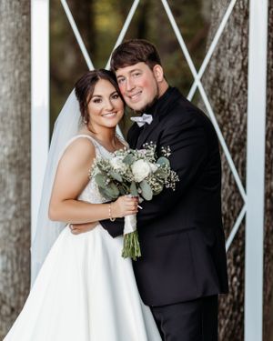 A couple in wedding attire shares a joyful moment among white pillars in an outdoor setting.  Middle TN wedding photographer