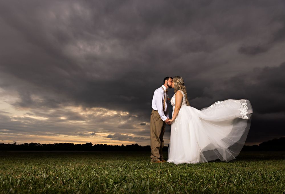 Dramatic wedding photos captured against stormy skies and open fields at sunset. Middle TN wedding photographer
