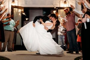 A couple performs a dramatic dip during their first dance at a wedding reception as guests watch and cheer.  Middle TN wedding photographer