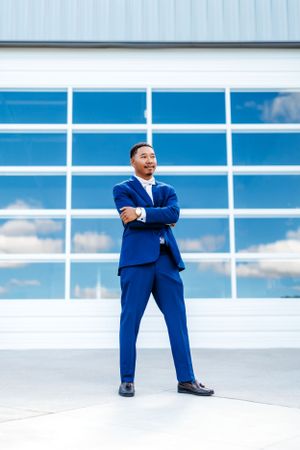 Groom in a bright blue suit strikes dynamic poses against a modern glass building backdrop with blue sky reflections.TN wedding photographer