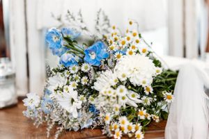 Elegant white + blue floral wedding bouquet with daisies and delphinium flowers on a rustic wooden table. Middle TN wedding photographer