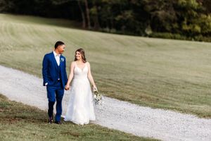 A couple walking together on a gravel path surrounded by lush green landscape.Middle TN wedding photographer