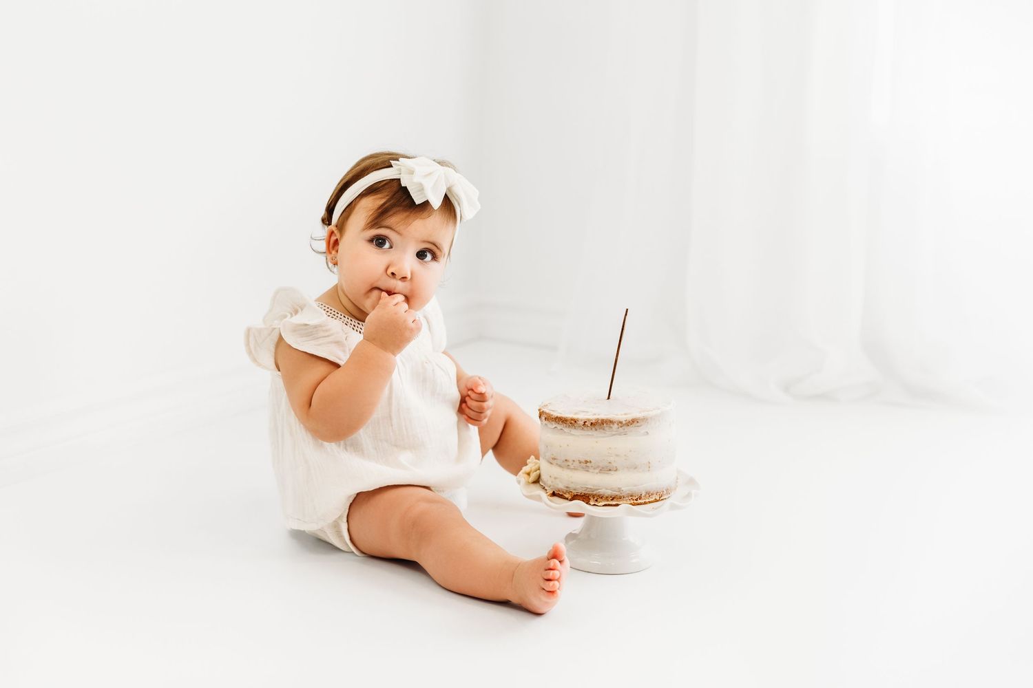 1 year old girl simple white cake smash, eating puffs