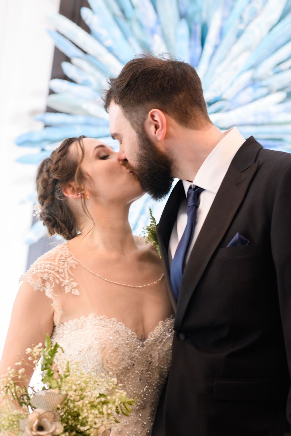 A romantic wedding kiss captured with a blue starburst background.