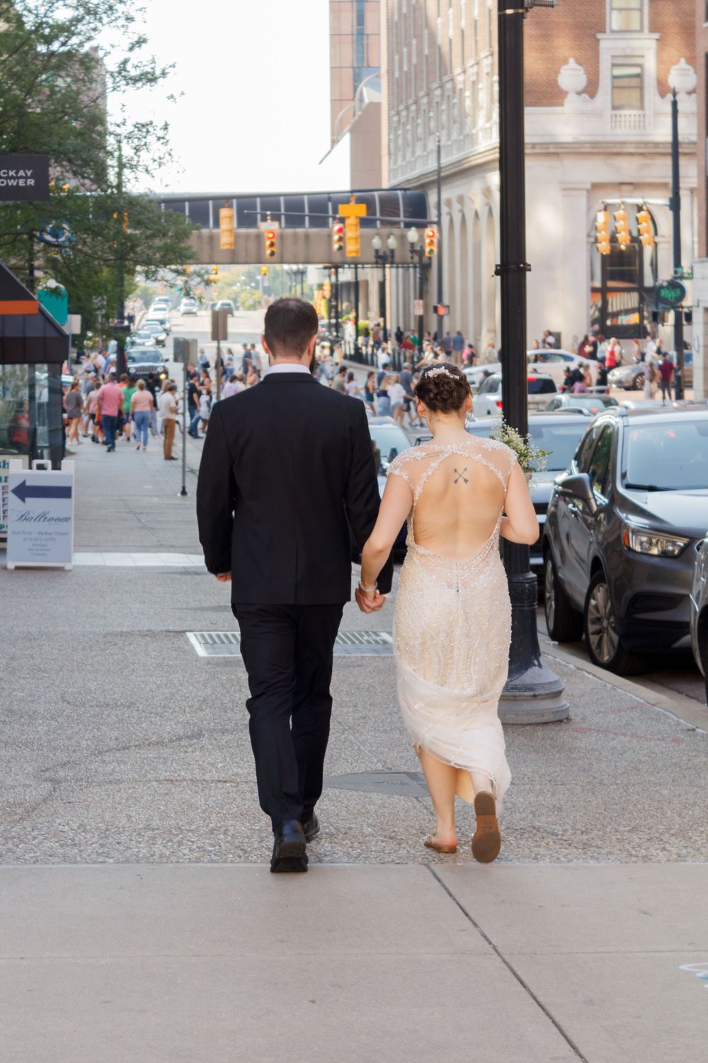 Couple walking hand in hand down a city street during their wedding day.