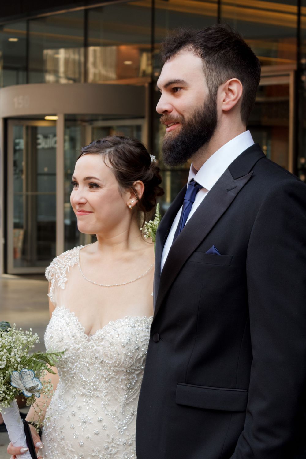A close-up shot of newlyweds in formal attire with the bride in a detailed lace gown.