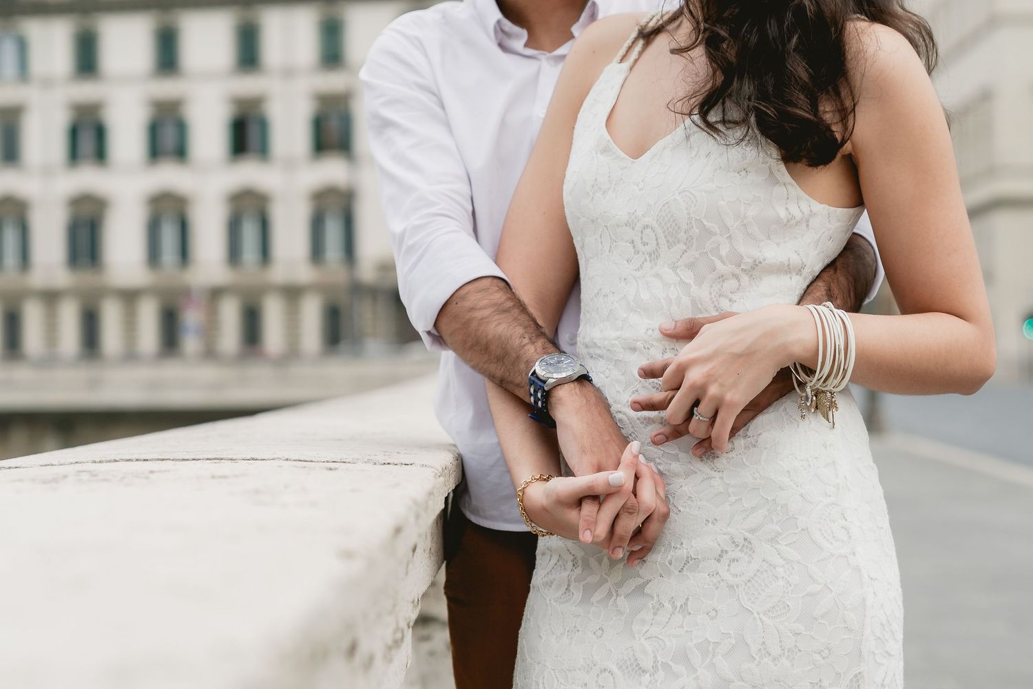 Close up of hands and lace dress details against classic European architecture.