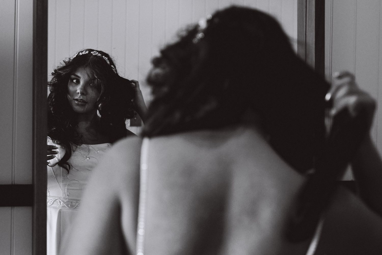 Artistic black and white reflection shot of bride getting ready in mirror.
