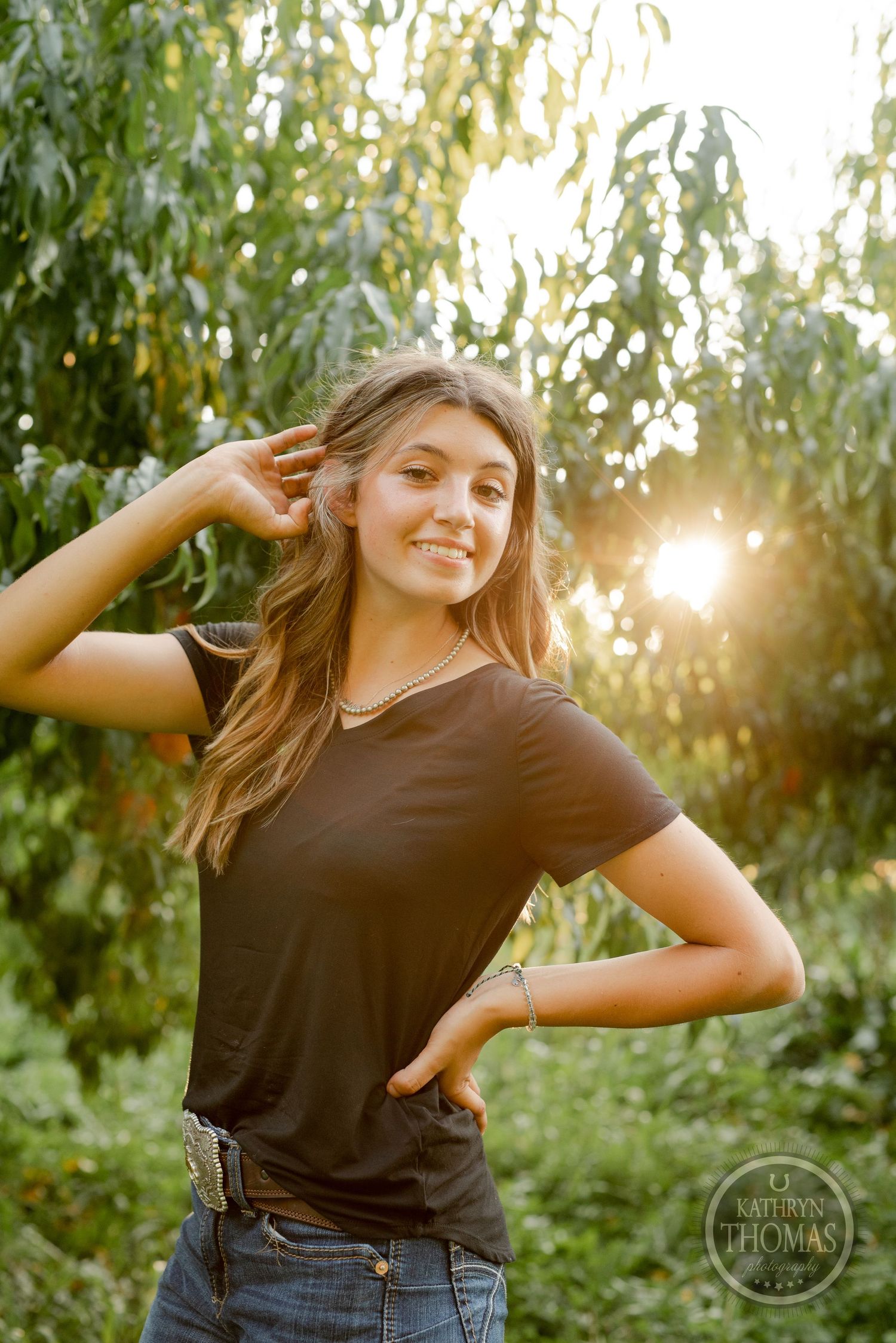 Casual outdoor portrait among peach trees with warm sunset lighting.