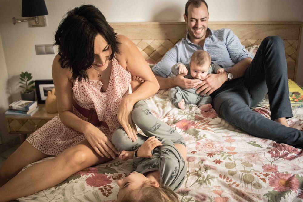 Family sharing playful moments together on a floral patterned bed.