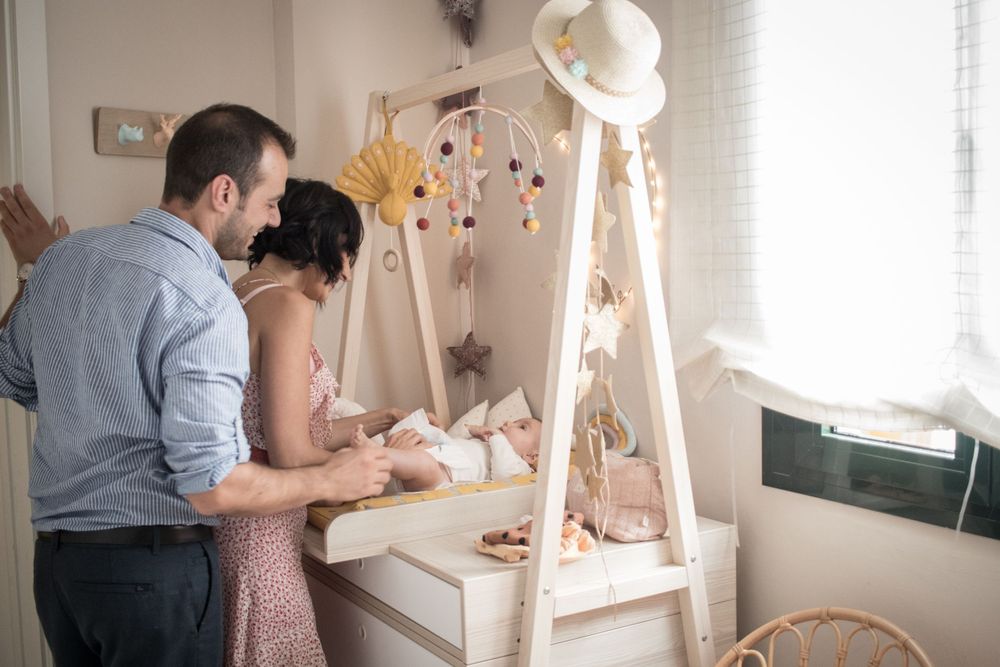 Couple looking at items on a white wooden display stand near a window.