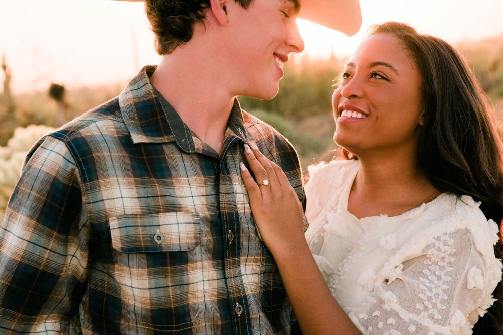 A romantic moment captured between a couple in casual attire during sunset.