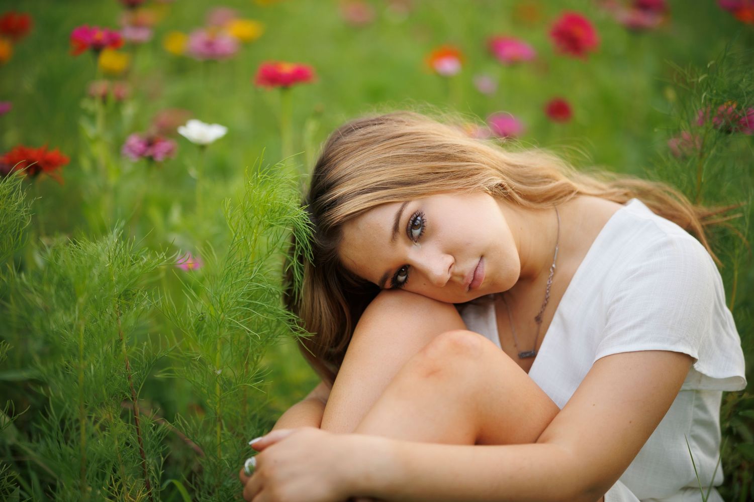 A dreamy portrait in a wildflower meadow with red poppies and green grass in soft focus.