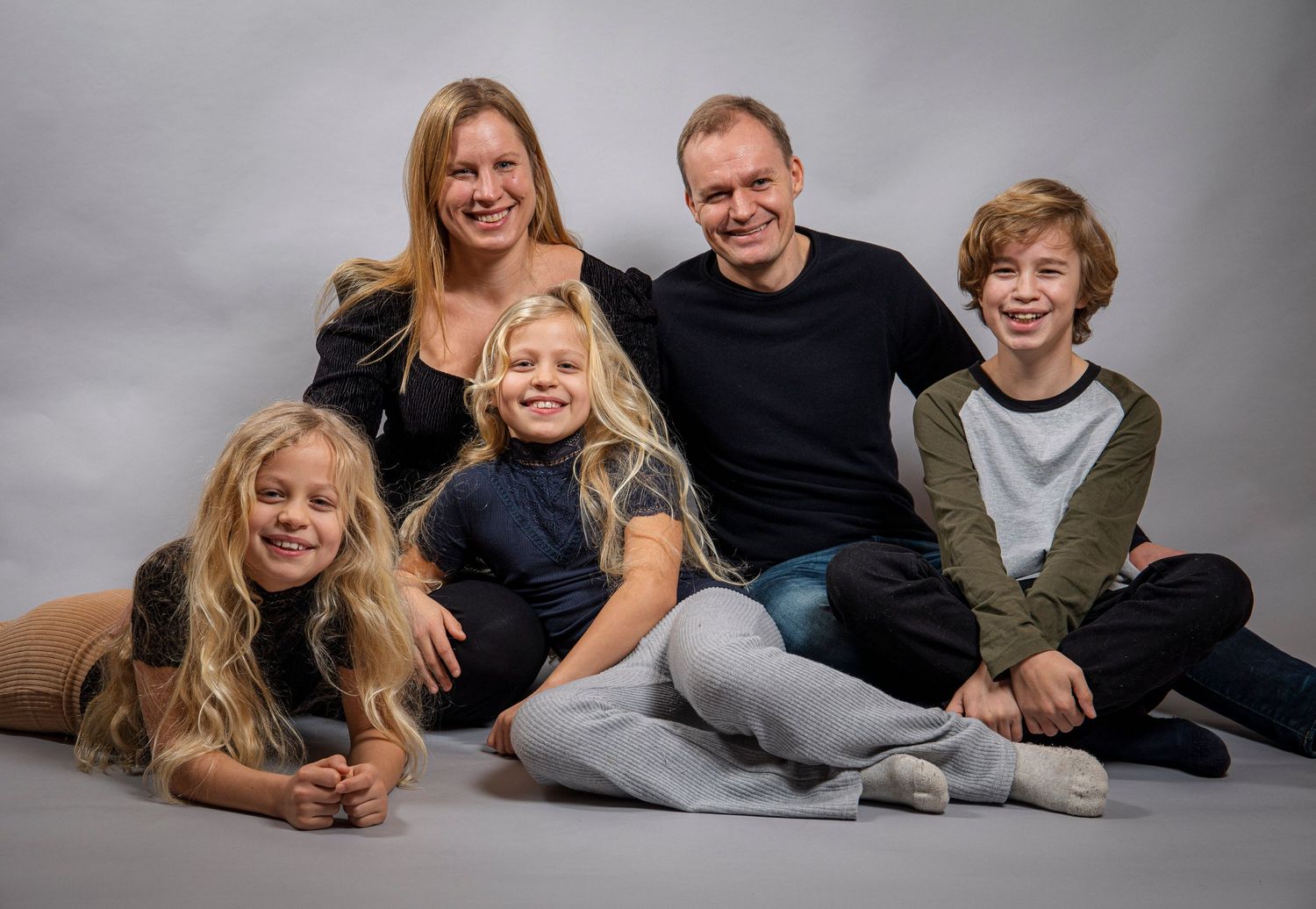 Happy family of five poses together in a professional studio portrait.