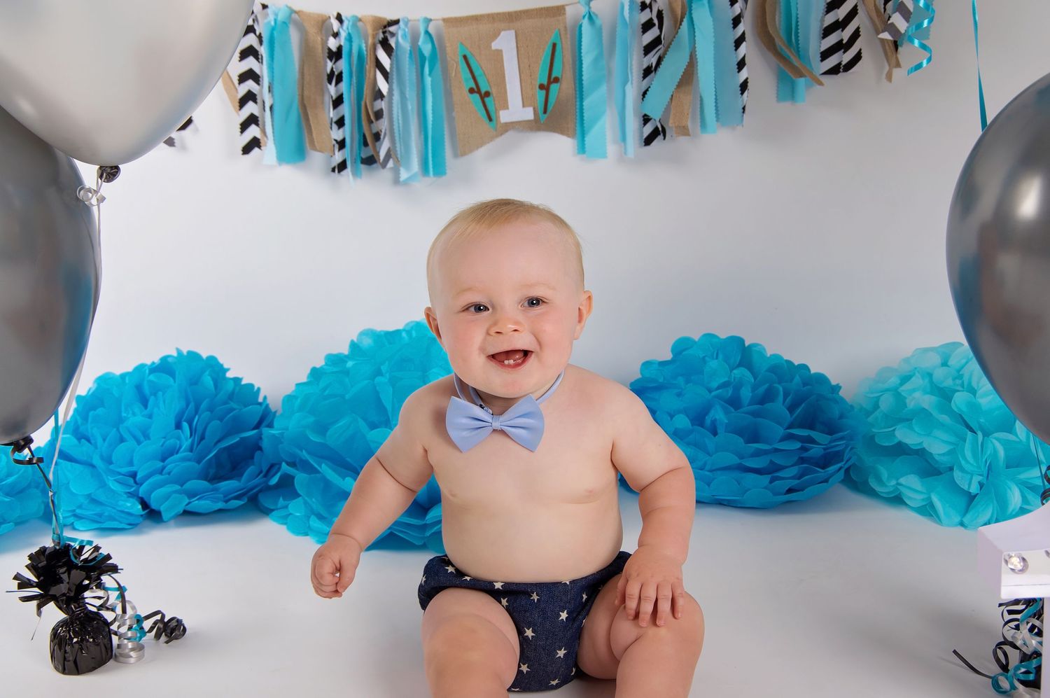 baby surrounded by decorations and balloons smiling