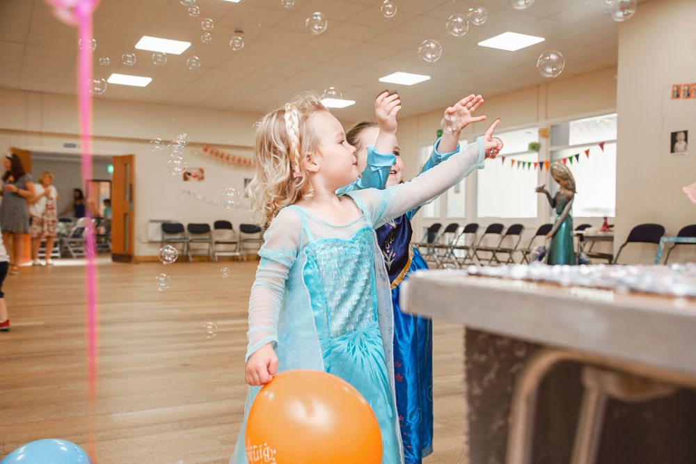 Birthday girl playing with bubbles at frozen themed birthday party