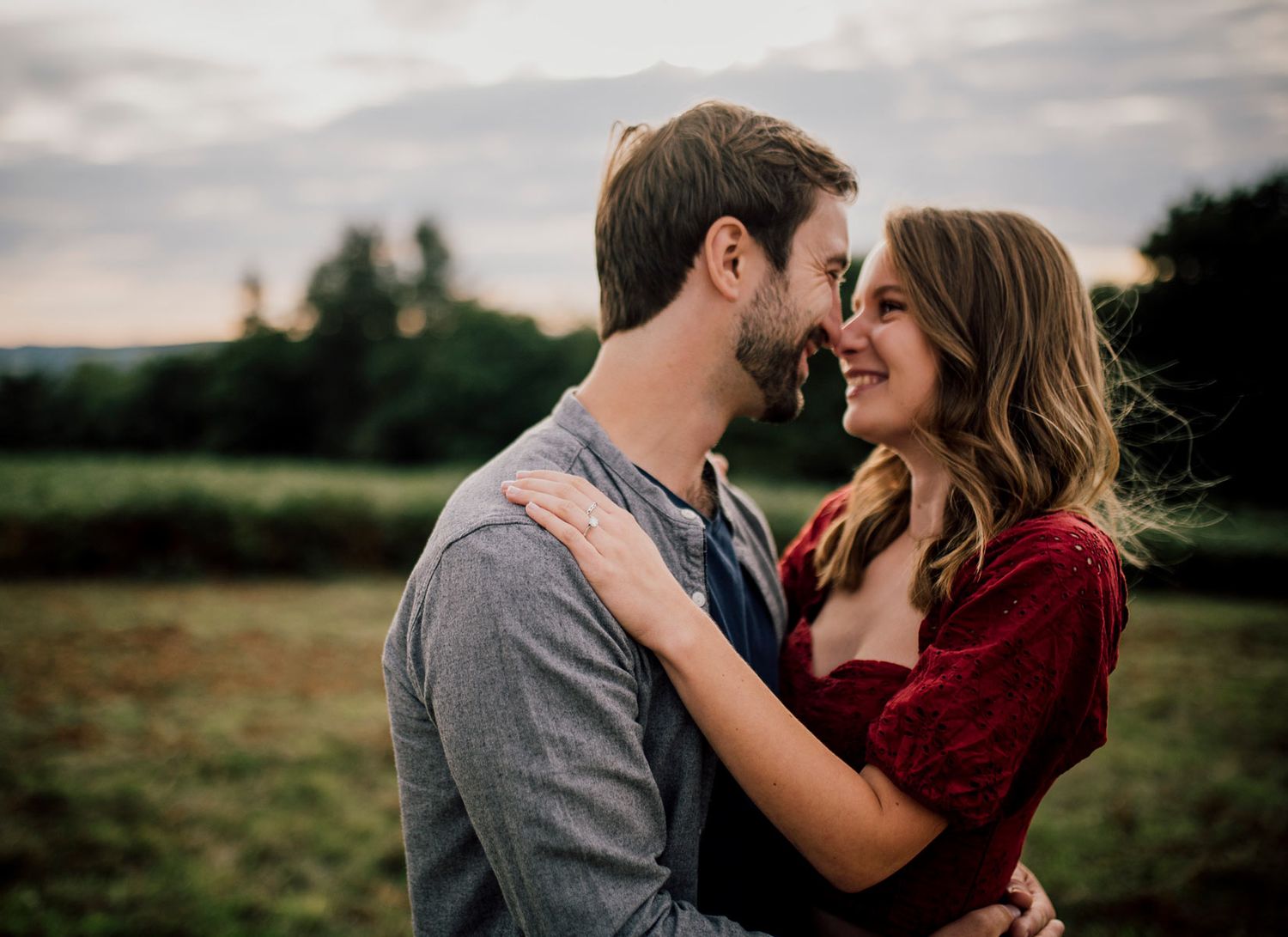 Romantic sunset engagement photos in field with couple in burgundy and grey outfits. Worcestershire Wedding photographer.